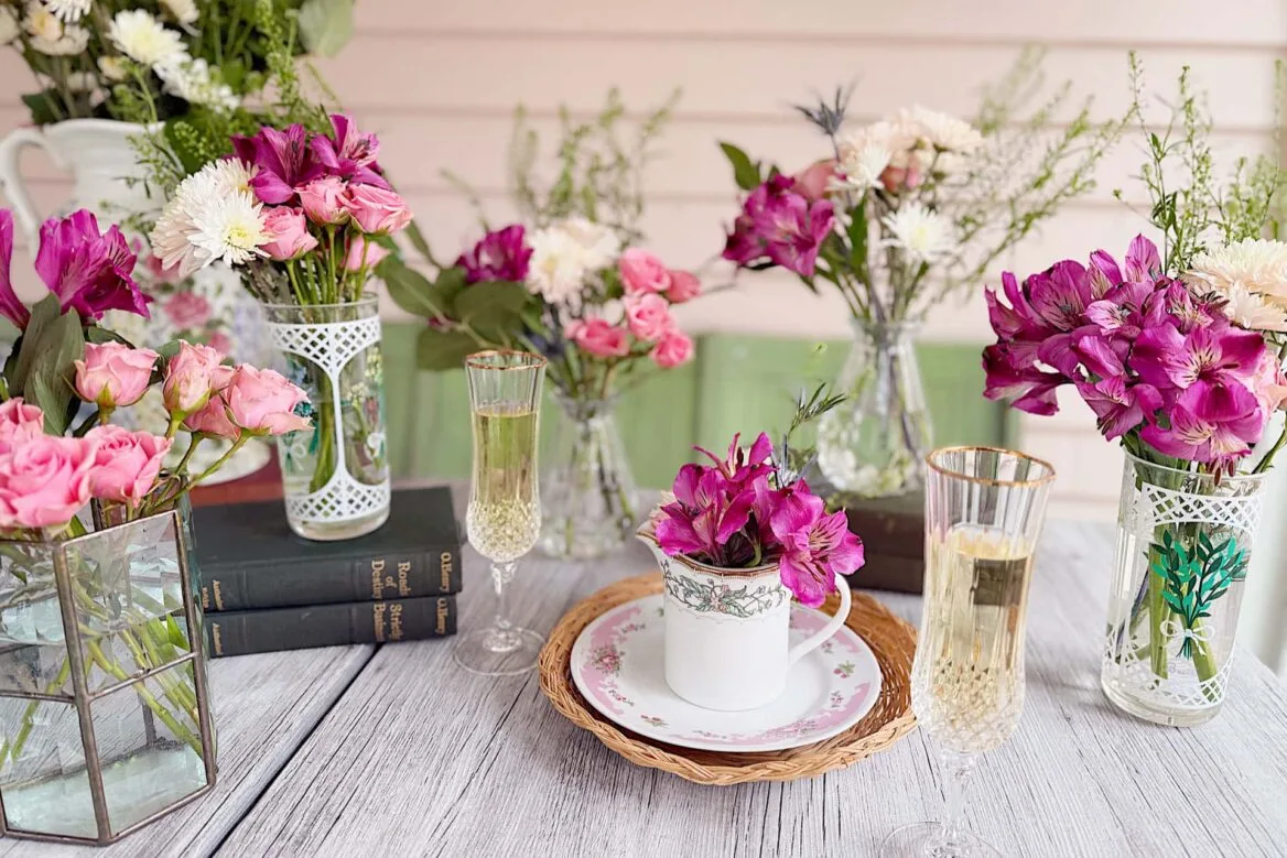 an arrangement of vases with pink and white flowers on a table